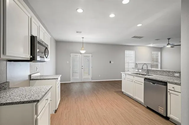 a kitchen with stainless steel appliances granite countertop hardwood floor sink stove and wooden cabinets