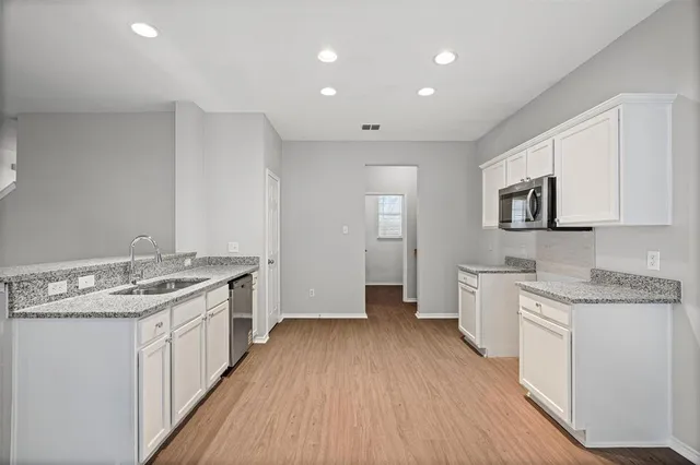 a kitchen with a hard wood floor white cabinets and white appliances