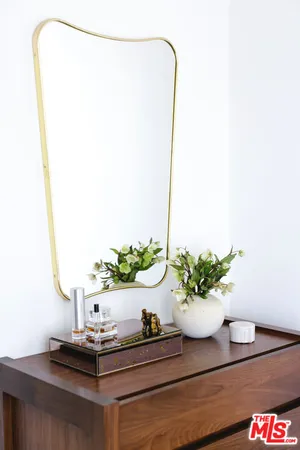a bedroom with a bed and a potted plant on the dresser