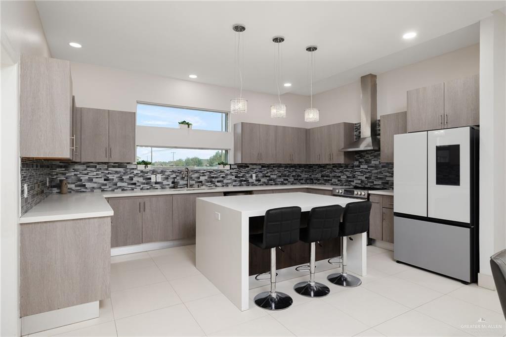 801 East Azucar Avenue Pharr, TX 78577 - Photo 7 of 19 Kitchen featuring a kitchen island, freestanding refrigerator, a breakfast bar area, wall chimney exhaust hood, and light countertops