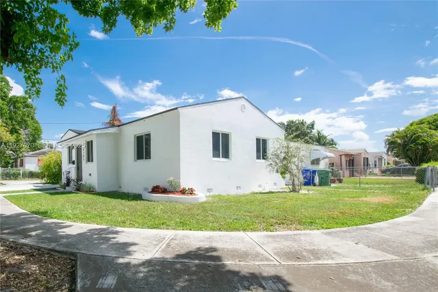 a view of a white house with a big yard and large trees