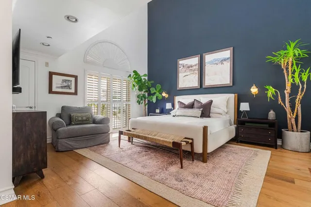 a bedroom with a bed couch and windows