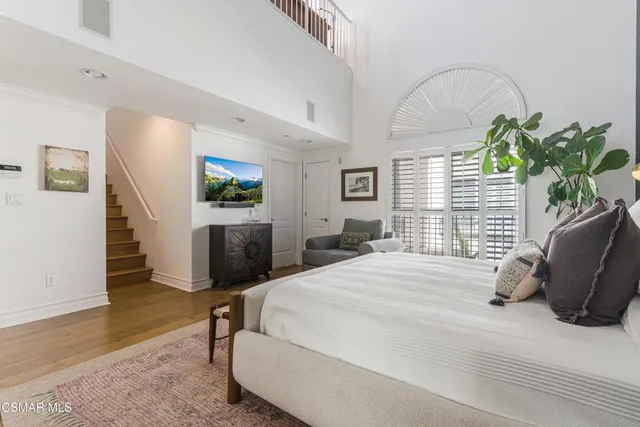 a bedroom with a bed potted plant with the wooden floor