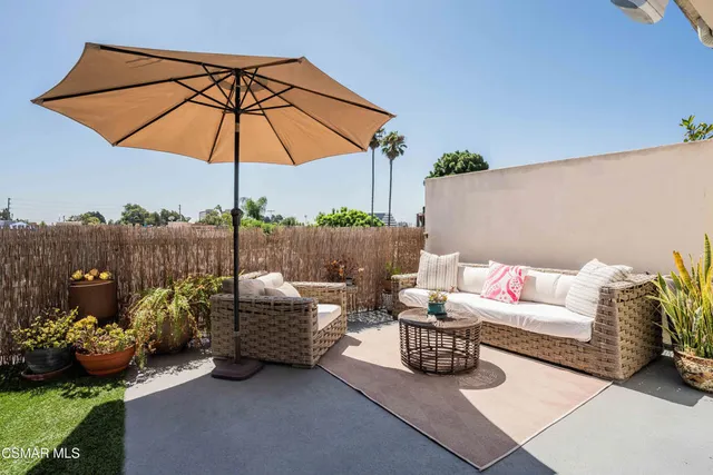 a view of a patio with couches table and chairs under an umbrella