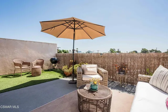 a view of a patio with couches table and chairs under an umbrella