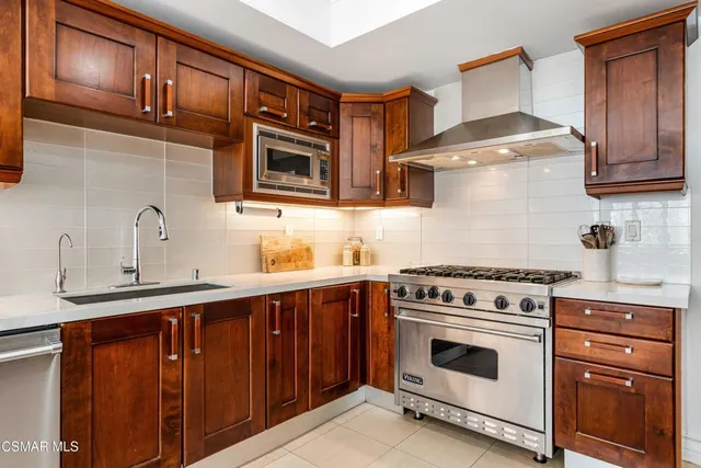 a kitchen with stainless steel appliances granite countertop wooden cabinets stove top oven and sink