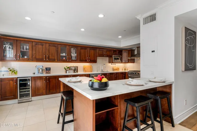 a kitchen with stainless steel appliances kitchen island granite countertop a table chairs sink and cabinets