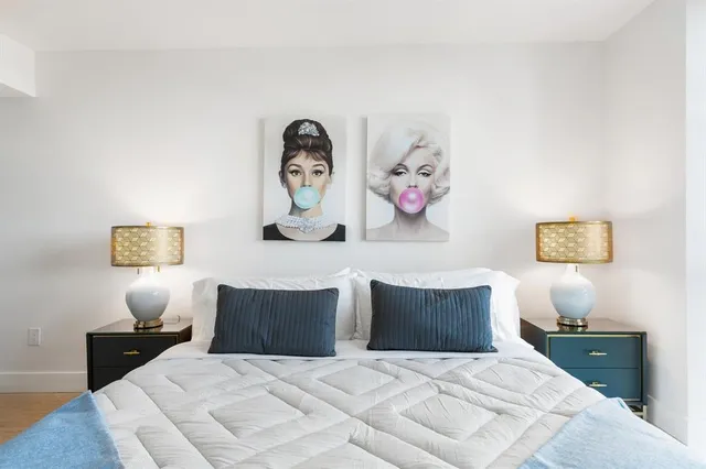 a bedroom with a bed and painting on the wall