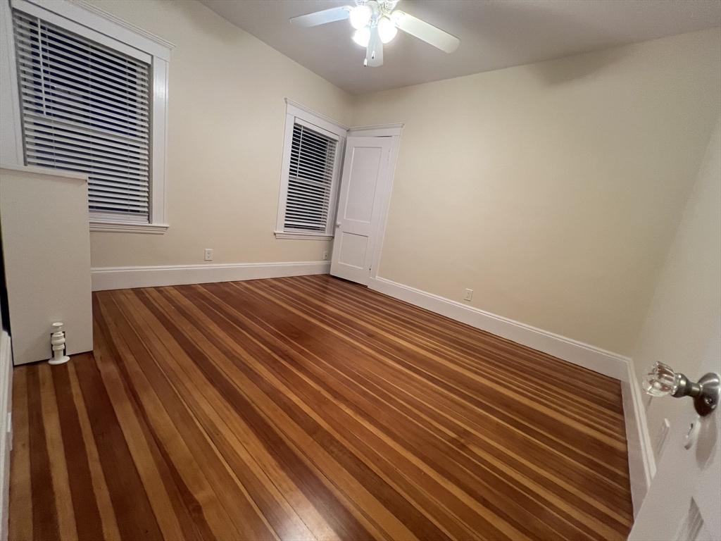 67 Commonwealth Road, Unit 1 Watertown, MA 02472 - Photo 20 of 22 a view of an empty room with wooden floor and a window