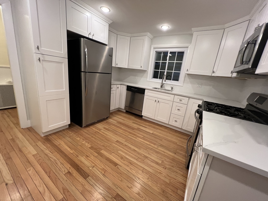 67 Commonwealth Road, Unit 1 Watertown, MA 02472 - Photo 2 of 22 a kitchen with granite countertop a refrigerator stove and sink
