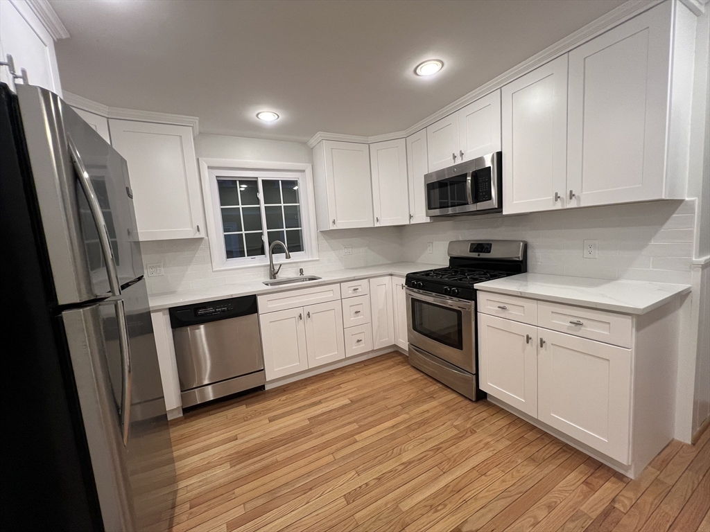 67 Commonwealth Road, Unit 1 Watertown, MA 02472 - Photo 3 of 22 a kitchen with white cabinets stainless steel appliances and a window