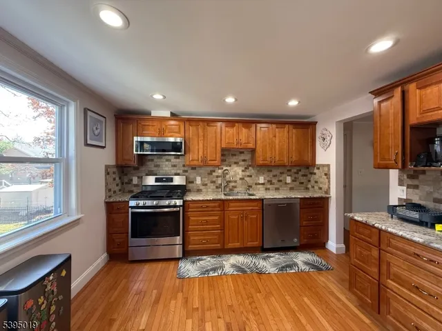 a kitchen with stainless steel appliances granite countertop a stove a sink and a refrigerator