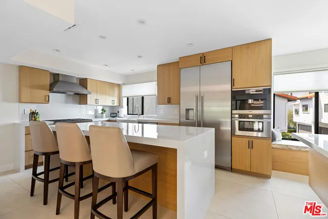 a kitchen with stainless steel appliances granite countertop a refrigerator a stove a sink a dining table and chairs with wooden floor