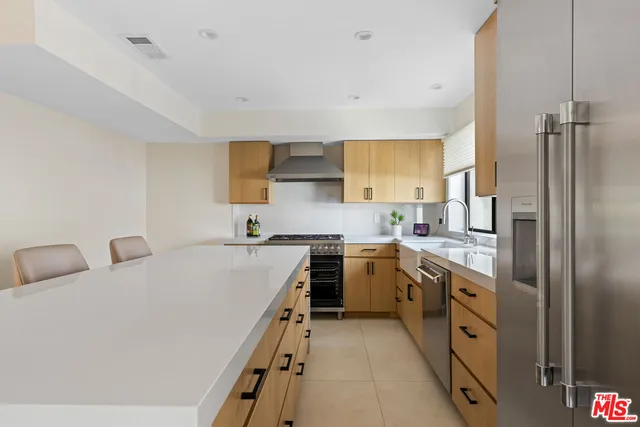 a large white kitchen with stainless steel appliances granite countertop a sink and a stove