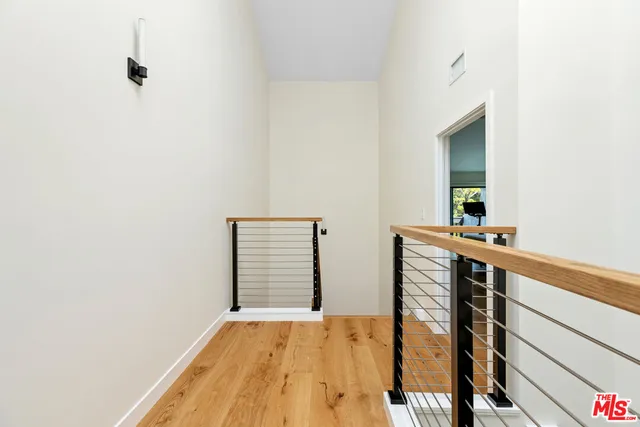 a view of a hallway with wooden floor and a bathroom