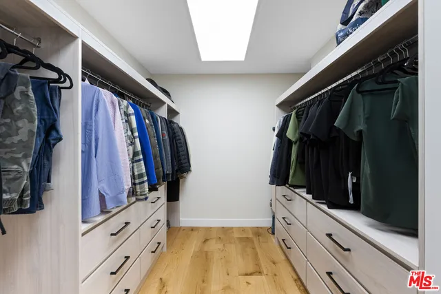 a view of walk in closet with clothes and shoes