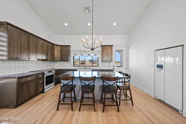 a kitchen with kitchen island a dining table chairs stainless steel appliances and cabinets
