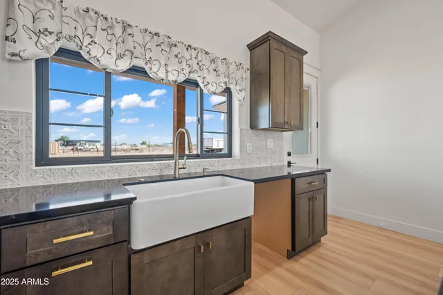 a kitchen with stainless steel appliances granite countertop a stove top oven a sink dishwasher a dining table and chairs with wooden floor