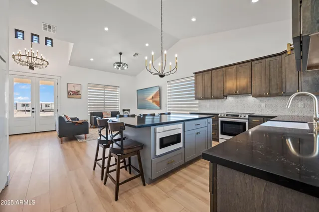a kitchen with stainless steel appliances granite countertop a sink a stove and a wooden floors
