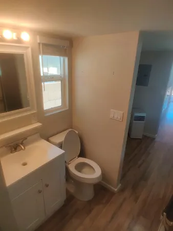 a bathroom with a toilet a sink a mirror and a window
