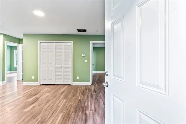 a view of an empty room with wooden floor and a window