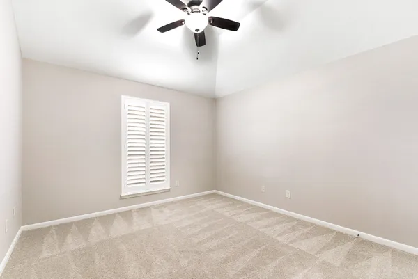 an empty room with a window and a fan