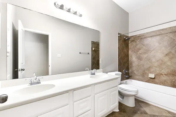 a bathroom with a double vanity sink toilet mirror and shower