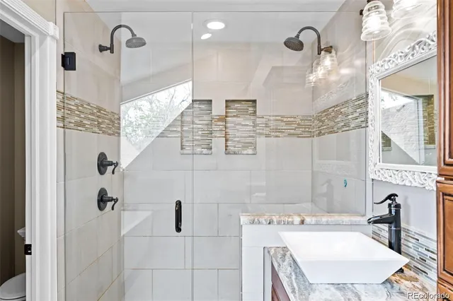 a bathroom with a sink a toilet a mirror and shower