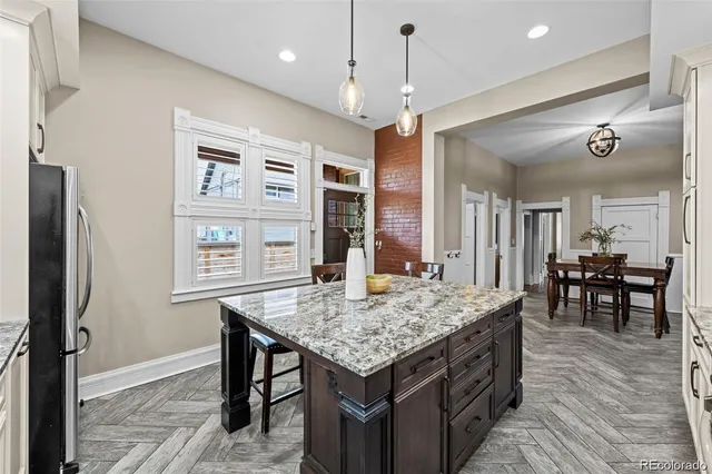 a kitchen with a table chairs refrigerator and wooden floor