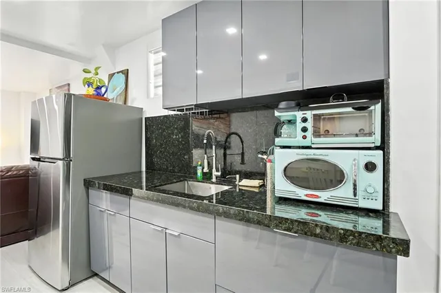 a kitchen with stainless steel appliances kitchen island granite countertop a sink and a refrigerator