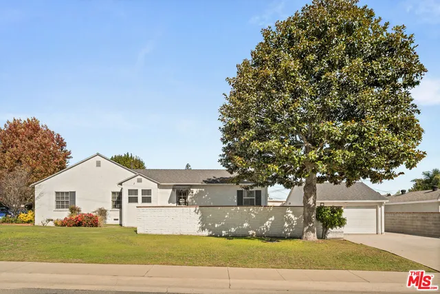 a front view of a house with a garden and trees