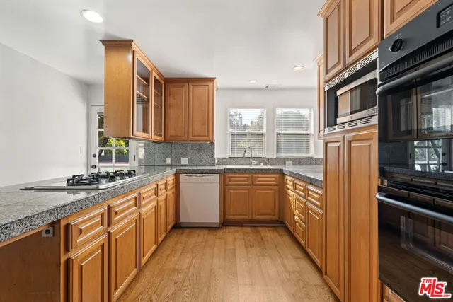 a kitchen with stainless steel appliances granite countertop a stove a sink and a refrigerator