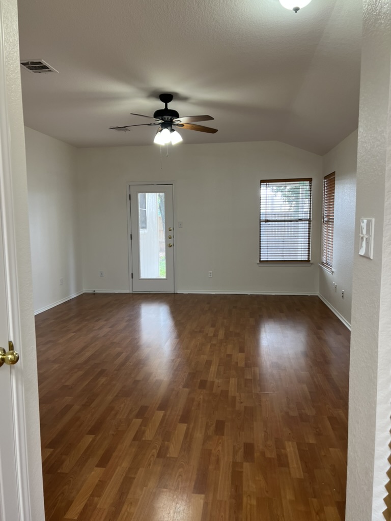 17843 Loch Linnhe Loop Pflugerville, TX 78660 - Photo 8 of 23 an empty room with wooden floor chandelier fan and windows