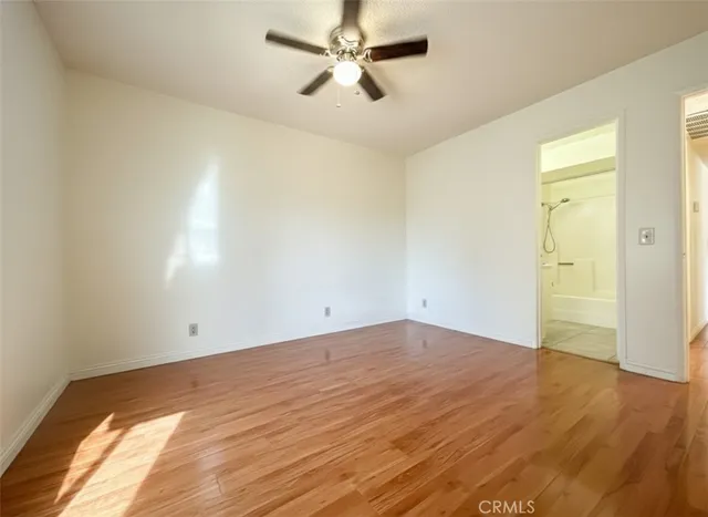 an empty room with wooden floor and a ceiling fan