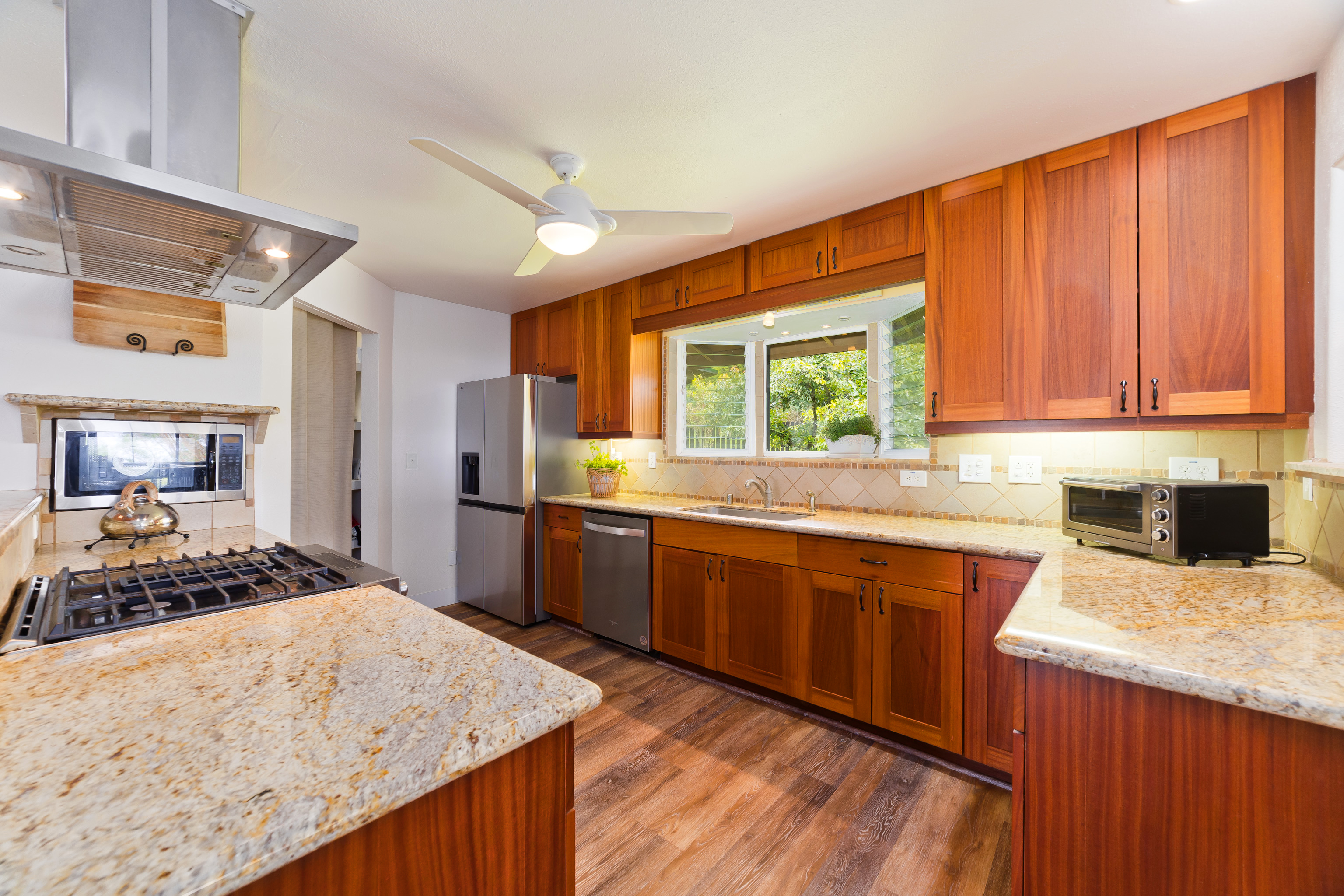 32-56 Piha Kahuku Road Ninole, HI 96773 - Photo 7 of 26 a kitchen with stainless steel appliances granite countertop wooden cabinets a stove and a sink
