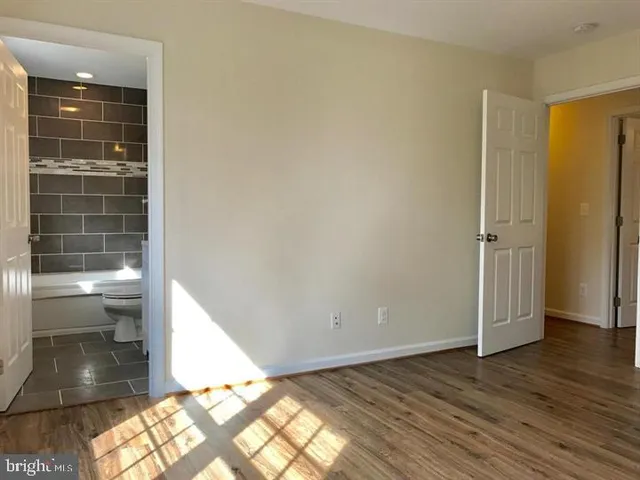 an empty room with wooden floor closet and windows