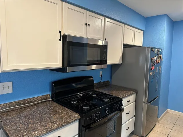 a kitchen with granite countertop a stove and a microwave