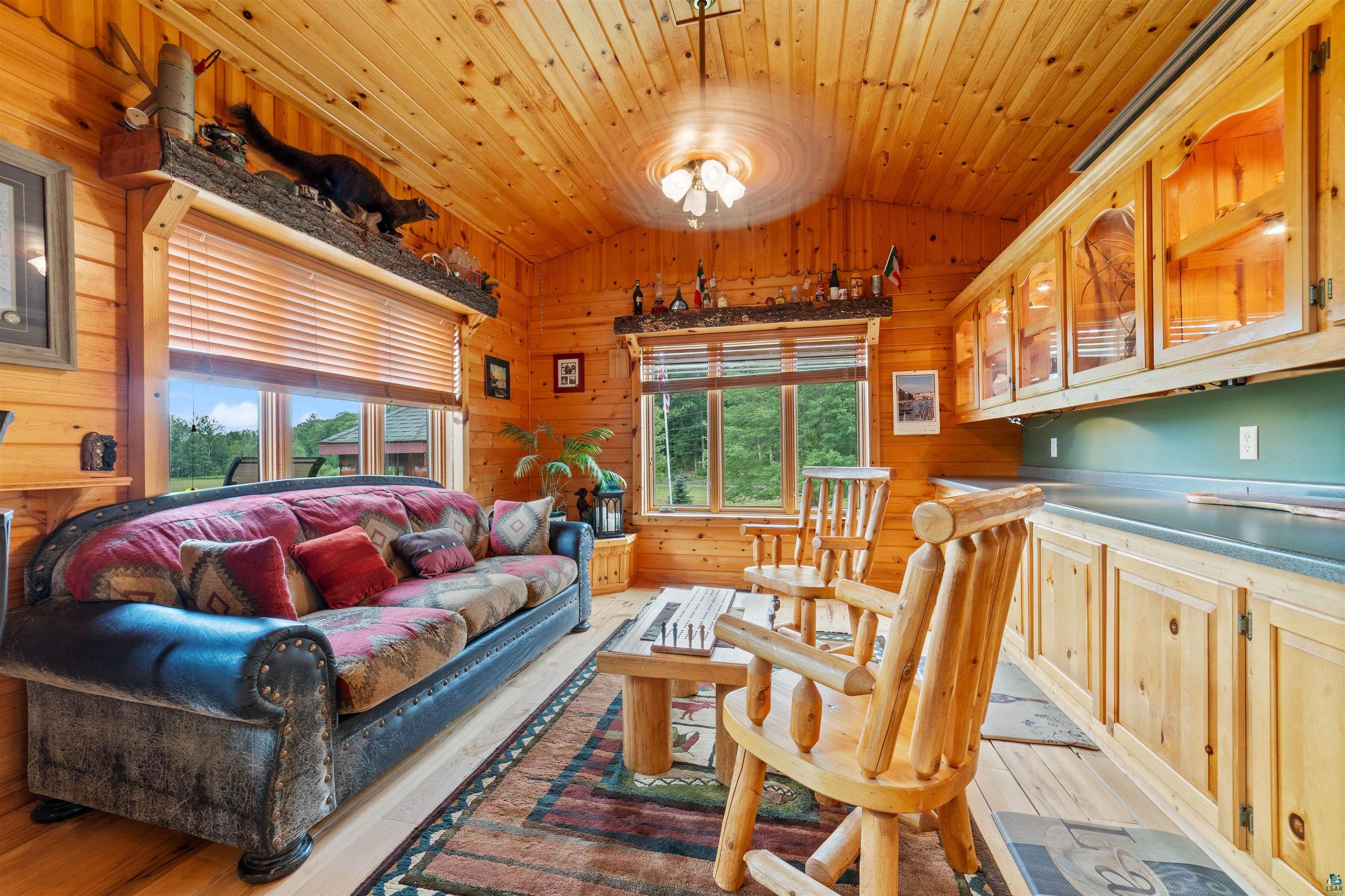 11911 East Rowe Road Lake Nebagamon, WI 54849 - Photo 17 of 61 Wood-paneled room featuring a sloped wood-plank ceiling, built-in cabinetry with glass-front uppers, and two large windows with horizontal blinds