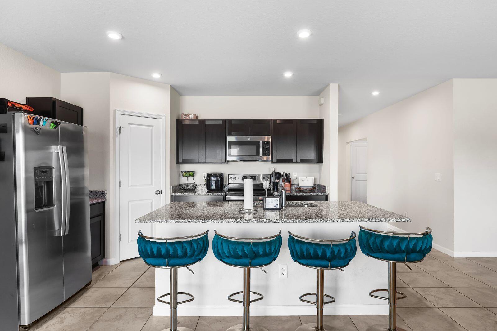 185 Dabou Loop Belle Glade, FL 33430 - Photo 6 of 25 a kitchen with stainless steel appliances kitchen island granite countertop a refrigerator and chairs