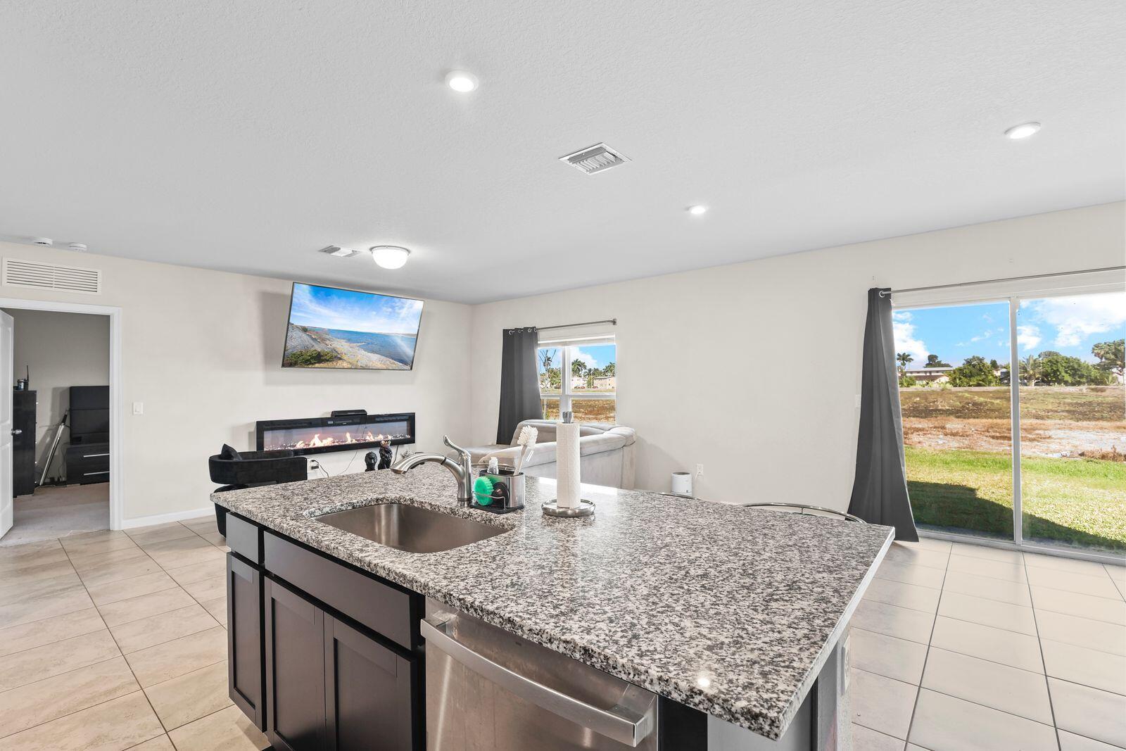 185 Dabou Loop Belle Glade, FL 33430 - Photo 8 of 25 a kitchen with stainless steel appliances granite countertop a sink stove and refrigerator