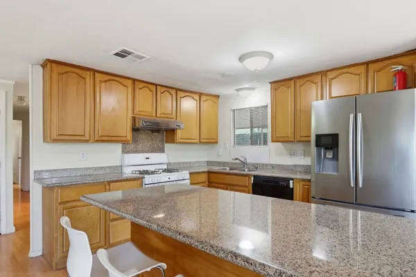 a kitchen with stainless steel appliances granite countertop a sink refrigerator and cabinets