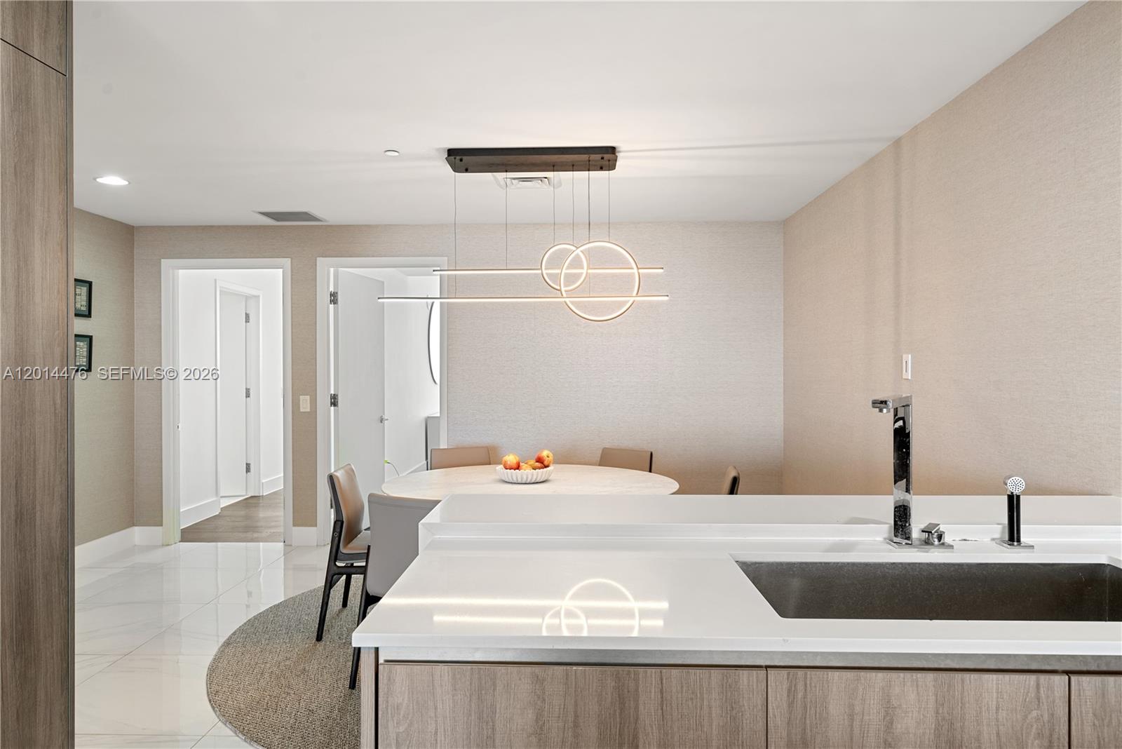 360 Ocean Drive, Unit 1106S Key Biscayne, FL 33149 - Photo 11 of 67 Dining Area – The dining area sits just off the kitchen and is accented by a sculptural modern chandelier. Neutral wallcovering, glossy flooring, and a rounded dining table create a polished setting for meals or casual gatherings.