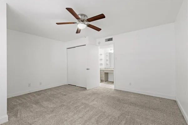 an empty room with closet and ceiling fan