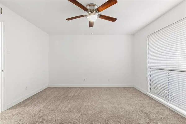 an empty room with a window and a ceiling fan