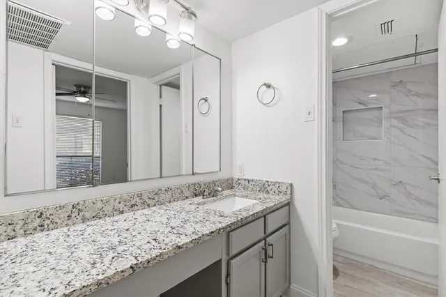 a bathroom with a granite countertop sink a mirror and a bathtub