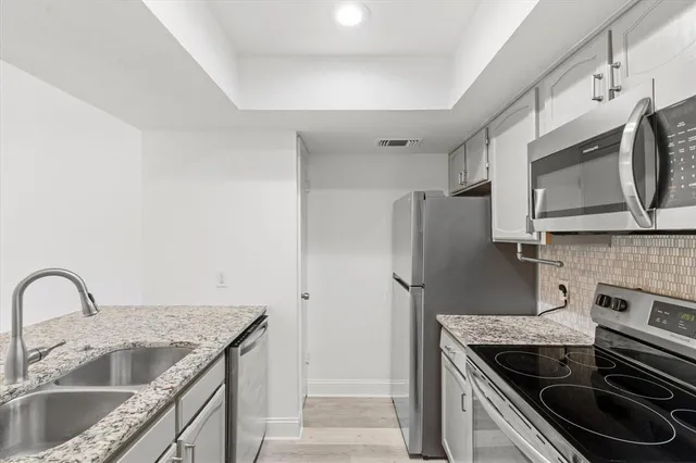 a kitchen with stainless steel appliances granite countertop a sink stove and refrigerator