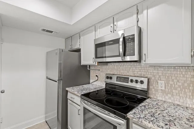 a kitchen with stainless steel appliances granite countertop a stove microwave refrigerator and sink