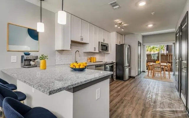 a kitchen with stainless steel appliances granite countertop a refrigerator a stove top oven a sink dishwasher and white cabinets with wooden floor
