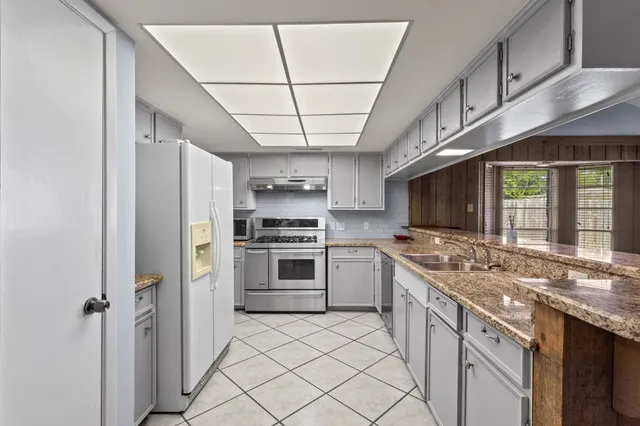 a kitchen with stainless steel appliances a sink cabinets and wooden floor