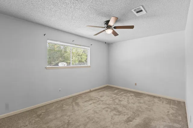 an empty room with a window and ceiling fan